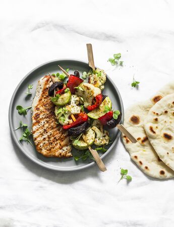 Grilled turkey chops, vegetables skewers and naan tortillas on a light background, top viewの写真素材
