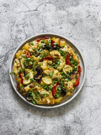 Roasted vegetables frittata - delicious appetizer, tapas, snack, breakfast on a grey background, top view. Cauliflower, bell peppers, mushrooms, zucchini, potatoes, eggs, cheese casseroleの写真素材