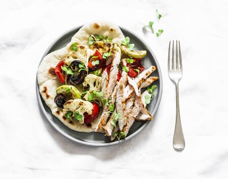 Naan flatbread with grilled roasted vegetables and turkey on a light background, top view. Delicious tapas, appetizers, snackの写真素材