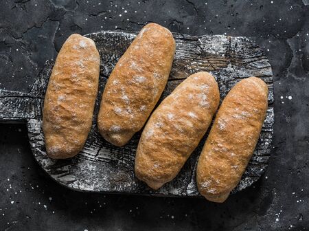 Homemade wholegrain bread rolls for sandwiches, hot dogs on a rustic cutting board, top viewの写真素材