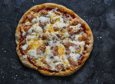 Whole grain dough salami, mozzarella, tomato sauce pizza on a dark background, top viewの写真素材