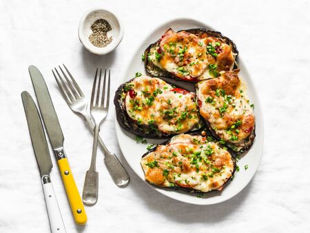 Baked aubergine with ham, tomatoes and mozzarella cheese - delicious appetizer, tapas on a light background, top viewの写真素材