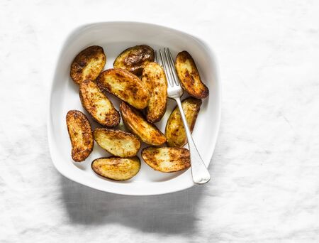 Baked new potatoes in baking dish on a light background, top view. Delicious snack, tapasの写真素材