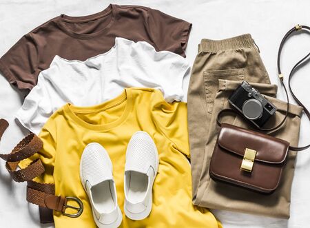 Women's clothing - three basic cotton t-shirts, sneakers, bag and loose trousers slouchy on a light background, top viewの写真素材