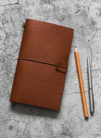 Leather brown personal organizer, pen, pencil  on a gray table, top view. Business concept, copy spaceの写真素材