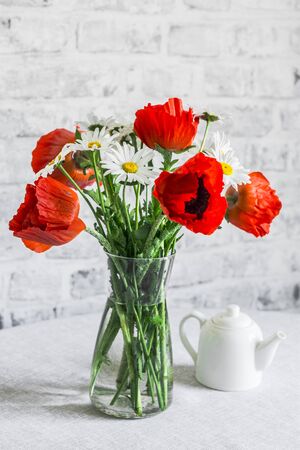 Bouquet of poppies and daisies on the table in a bright room. Home interior beauty comfort conceptの写真素材