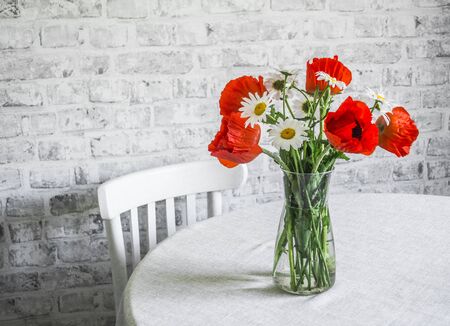 Cozy interior home - bouquet of poppies and daisies in a vase on the table, vintage wooden chair in a bright room. Beauty flowers still lifeの写真素材