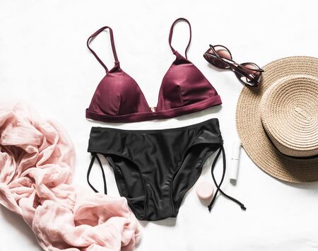 Women's bikini, hat, sandals, headscarf, sunglasses on a light background, top view. Vacation sea fashion beauty conceptの写真素材