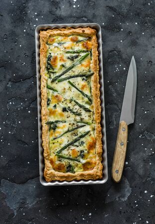 Asparagus, spinach, mozzarella, potato tart in a baking dish on a dark background, top viewの写真素材