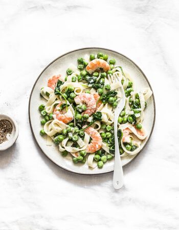 Delicious lunch - green peas, shrimps, spinach, cream sauce tagliatelle pasta  on a light background, top viewの写真素材
