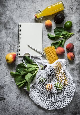 Healthy food planning concept. Eco bag, fruits, vegetables, greens and empty notebook on a gray background, top view with copy space. Flat layの写真素材