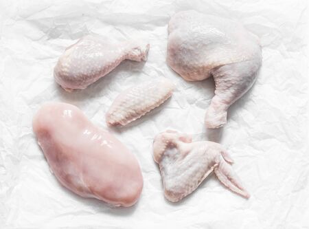 Pieces of raw butchered chicken - legs, thighs, breast, wing on a light background, top view. Raw food ingredients for cookingの写真素材