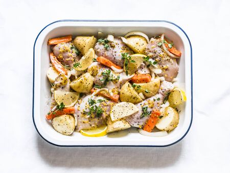 Cooking chicken with new potatoes, carrots, lemon, thyme in white wine. Raw food, on a light background, top viewの写真素材
