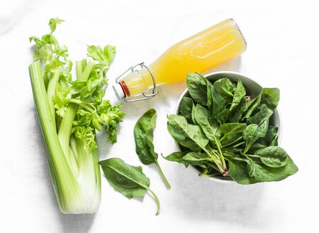Ingredients for detox smoothies - fresh celery, spinach, natural orange juice on a light background, top viewの写真素材