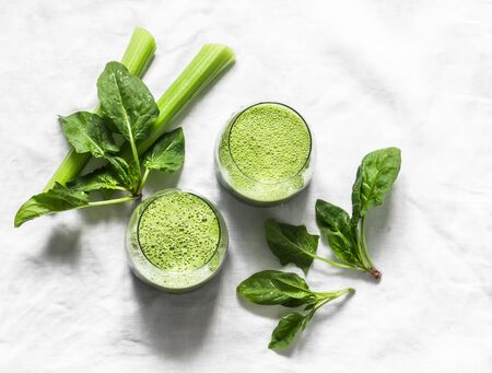 Detox diet food vegetarian concept.  Freshness celery, spinach, natural orange juice green smoothies on a light background, top view. Copy space, flat layの写真素材