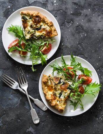 Pie slices with canned tuna, mozzarella, spinach, potatoes and mizuna tomatoes salad on dark background, top viewの写真素材
