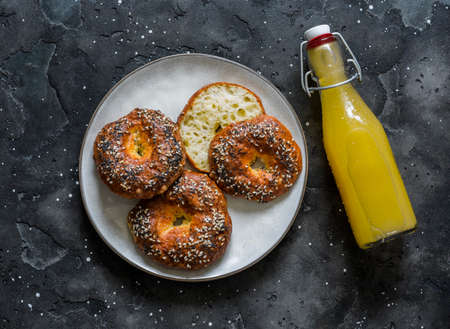 Delicious snack, brunch - cheesy rolls and a bottle of freshly squeezed orange juice on a dark background, top viewの写真素材