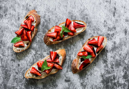 Bruschetta, sandwiches with strawberries, cream cheese and balsamic sauce on a grey background, top view. Delicious appetizer, tapasの写真素材