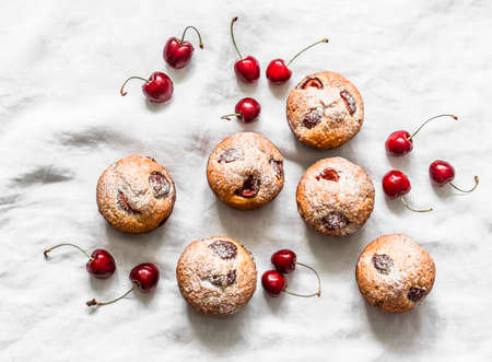 Homemade cherry muffins and fresh cherries on a light background. the view from the top. Delicious dessertの写真素材