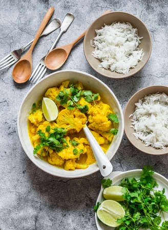 Indian food lunch table - vegetarian cauliflower curry sauce, rice, cilantro, lime on gray background, top viewの写真素材