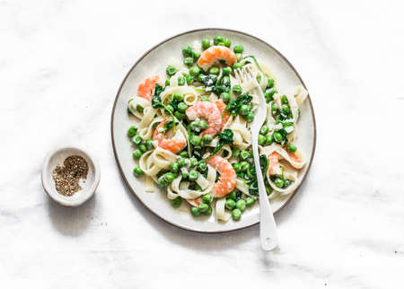 Green peas, shrimps, spinach, cream sauce tagliatelle pasta on a light background, top viewの写真素材