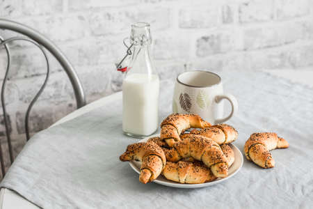 Poppy seeds croissants and a bottle of milk on the kitchen table. Delicious breakfast, snackの写真素材
