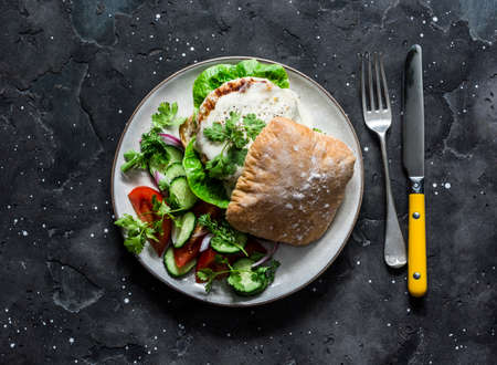 Ciabatta roll bread sandwich burger with chicken cutlet and mayonnaise mustard sauce and vegetables salad on a dark background, top viewの写真素材