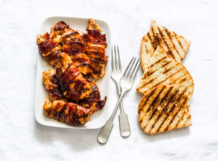 Delicious - roasted bbq chicken breast wrapped in ham, grilled bread on a light background, top viewの写真素材