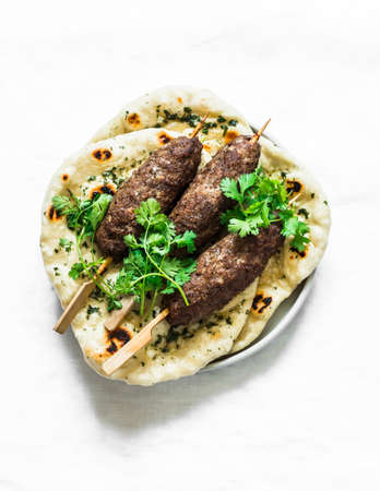 Grilled kebab and garlic herb flatbread naan on a light background, top view. Delicious tapasの写真素材
