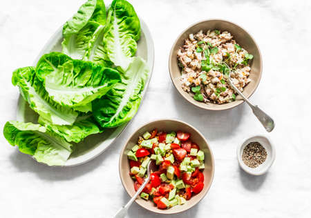 Ingredients for cooking - romaine salad and tuna, egg, tomato, avocado salad on a light background, top view. Delicious appetizer, tapas, snackの写真素材