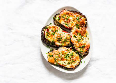 Roasted eggplant steak with ham, tomatoes and mozzarella cheese - delicious appetizer, tapas on a light background, top viewの写真素材