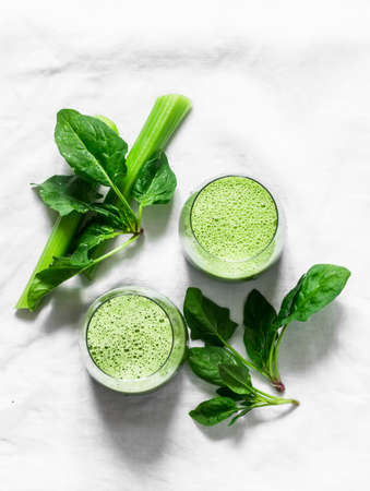 Healthy diet vegetarian concept. Fresh celery, spinach, natural orange juice green smoothies on a light background, top view. Copy space, flat layの写真素材