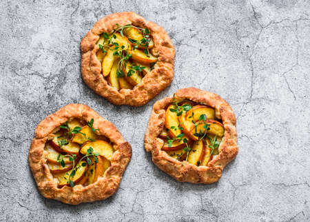 Ripe peaches, fresh thyme mini pies galettes - delicious summer pastry dessert on a gray background, top viewの写真素材