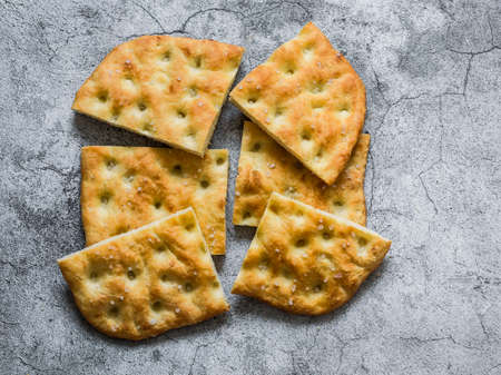 Homemade crunchy italian focaccia on a gray background, top view. Traditional italian bread