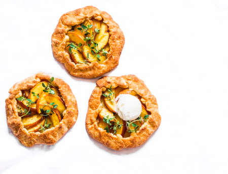 Ripe peaches, fresh thyme mini pies with cream ice cream - delicious summer sweet dessert on a light...