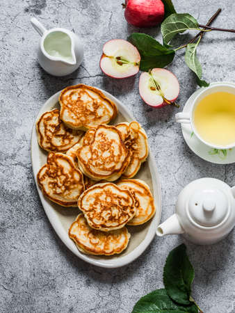 Delicious breakfast - apple pancakes, green tea, fresh apples, cream on a gray background, top viewの写真素材