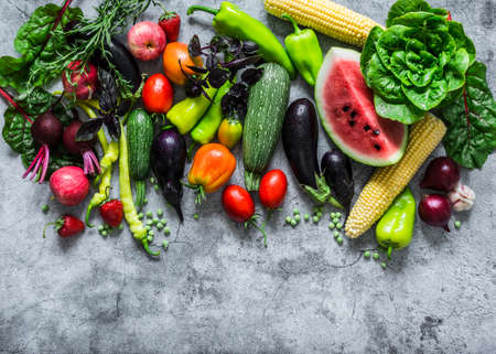 Fresh garden organic vegetables, berries, fruits on a gray background, top view. Healthy diet vegetarian food concept. Flat lay, copy spaceの写真素材