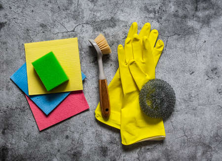 Home cleaning equipment - rubber gloves, sponges, brushes, rags on a gray background, top view. Copy spaceの写真素材