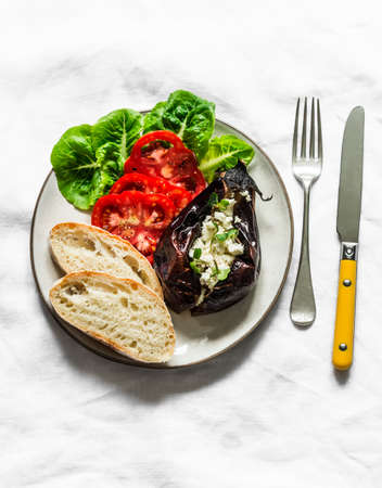 Greek style roasted eggplant with feta cheese, tomatoes, green salad, homemade bread - delicious appetizer, tapas, snack on a dark background, top viewの写真素材