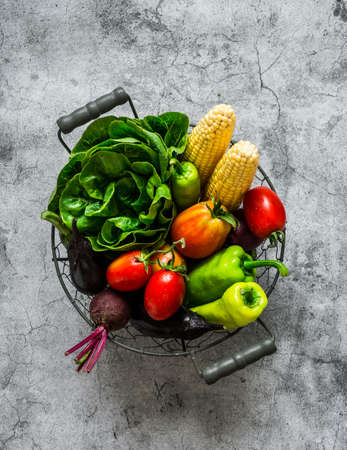 Metal basket with fresh organic garden vegetables on a gray background, top view. Copy spaceの写真素材