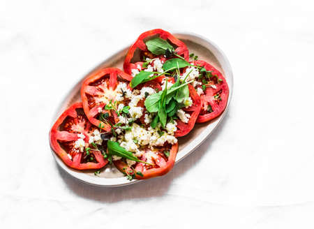 Fresh tomatoes, arugula, feta cheese appetizer salad on a light background, top viewの写真素材