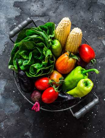 Metal basket with fresh organic garden vegetables on a dark background, top view. Copy spaceの写真素材