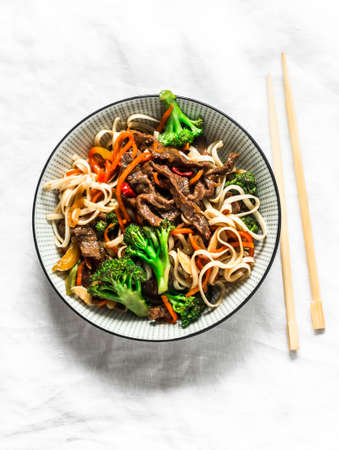 Udon noodles with beef and vegetables - delicious lunch on a light background, top view. Balanced...