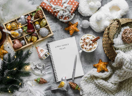 Christmas cozy home background. Christmas planning notepad, toys, hot chocolate, slippers, basket...