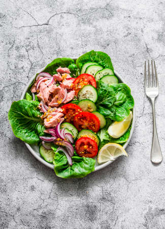 Canned tuna, tomatoes, cucumbers, romaine salad, red onion, olive oil salad - delicious healthy food on a gray background, top viewの写真素材