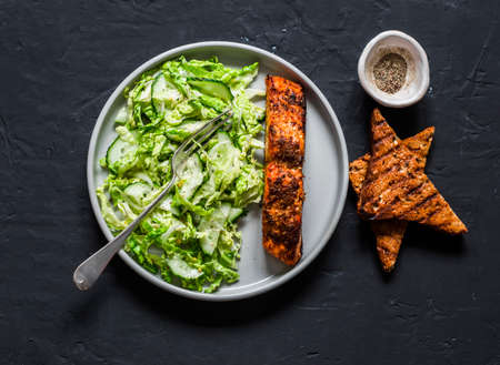 Baked teriyaki salmon and savoy cabbage, cucumber salad on dark background, top view. Healthy diet foodの写真素材