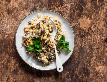 Delicious vegetarian lunch - couscous with fried mushrooms on a wooden background, top viewの写真素材