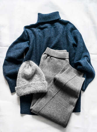 Women's clothing - blue sweater with a high neck, gray knitted sports pants and a hat on a light background, top viewの写真素材