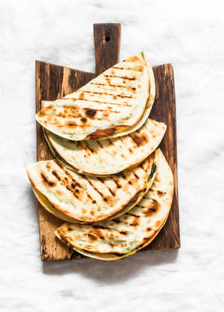Spinach and mozzarella cheese vegetarian grilled quesadilla on a light background, top viewの写真素材
