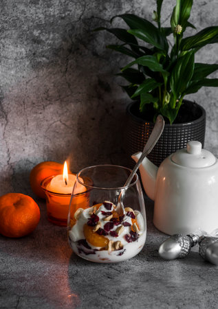 Cozy home still life. Greek yogurt with tangerine, dried cranberries and nuts on a gray background, top viewの写真素材